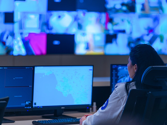 control room operator sitting at a desk looking at computer screens.