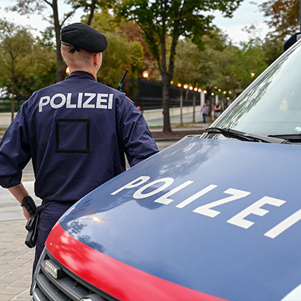 german police officer standing in front of his police car on a parking lot